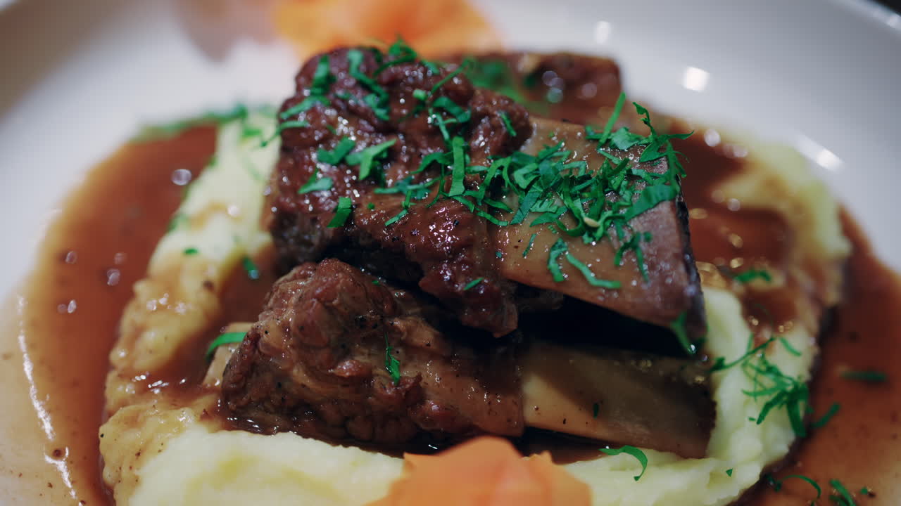 Nærbillede af en gourmet kødret serveret på cremet kartoffelmos med fyldig sauce og krydderurter