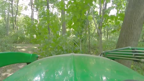 POV-Del-Operador-Del-Equipo-Conduciendo-Un-Cargador-Con-Horquillas-Empujando-Un-árbol-Pequeño-A-Lo-Largo-De-Un-Sendero-A-Través-Del-Bosque-En-Un-Día-Soleado-En-Illinois