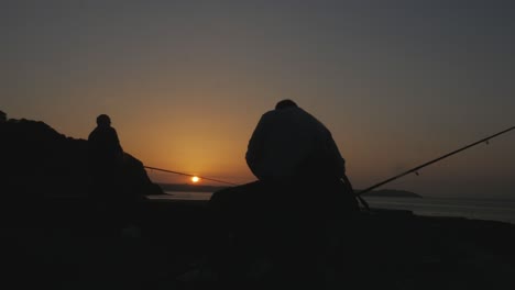 artistic silhouette of fishermen casting their rods at sunrise, early bird catches the worm concept