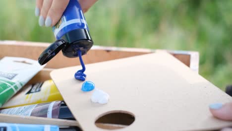 a person squeezing paint onto a palette