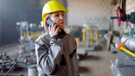 Blonde-Frau-Mit-Gelbem-Helm-In-Der-Fabrik