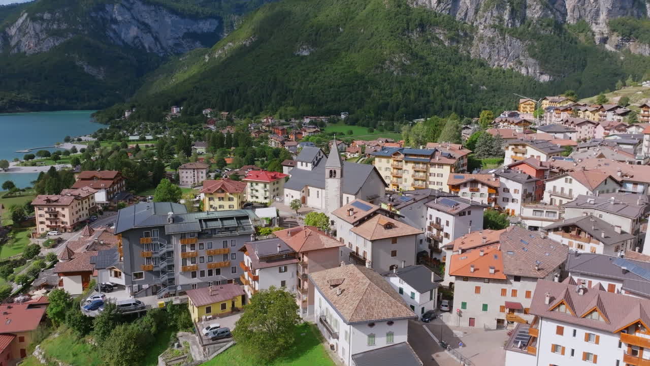 Aerial footage rotating around a church spire in the center of the town of Molveno in northern Italy.