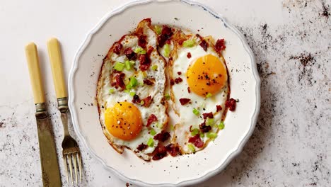 two fresh fried eggs with crunchy crisp bacon and chive served on rustic plate