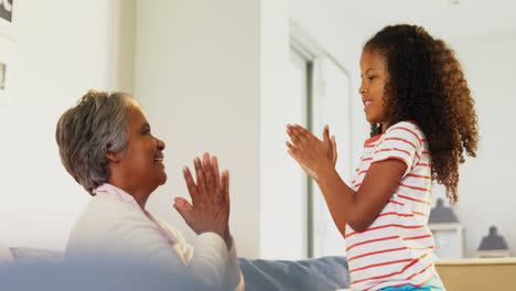 Granddaughter-and-grandmother-playing-clapping-games-in-living-room-4k