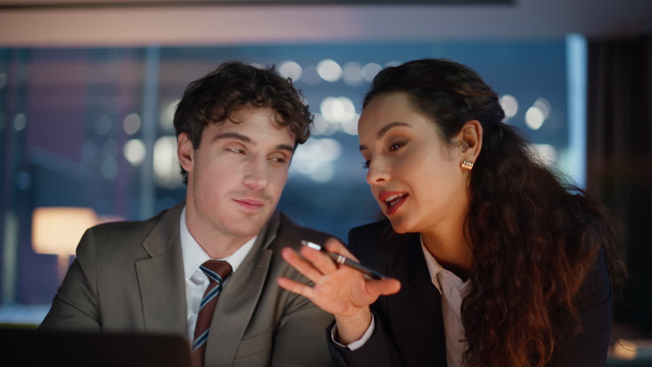 Charming office couple laughing at dark workplace looking computer portrait