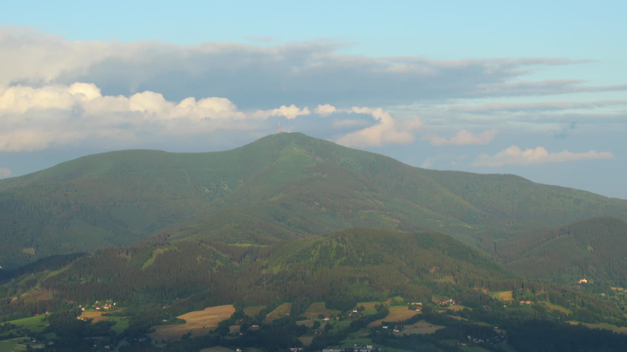 두꺼운 구름이 움직이는 백그라운드에서 화창한 날 동안 대형 무선 송신기 보기가 있는 라이세 산 정상 내부를 확대합니다.