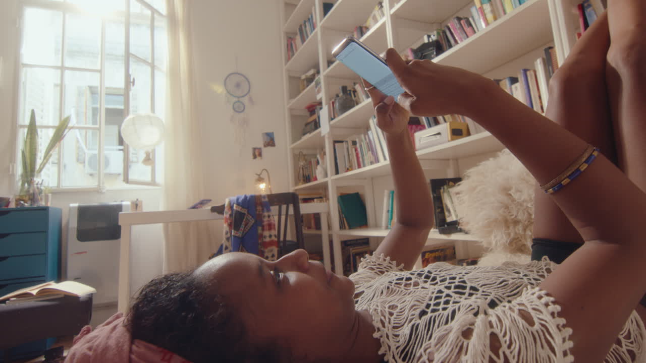 Girl Lying on Bed with Legs Up and Texting on Phone at Home