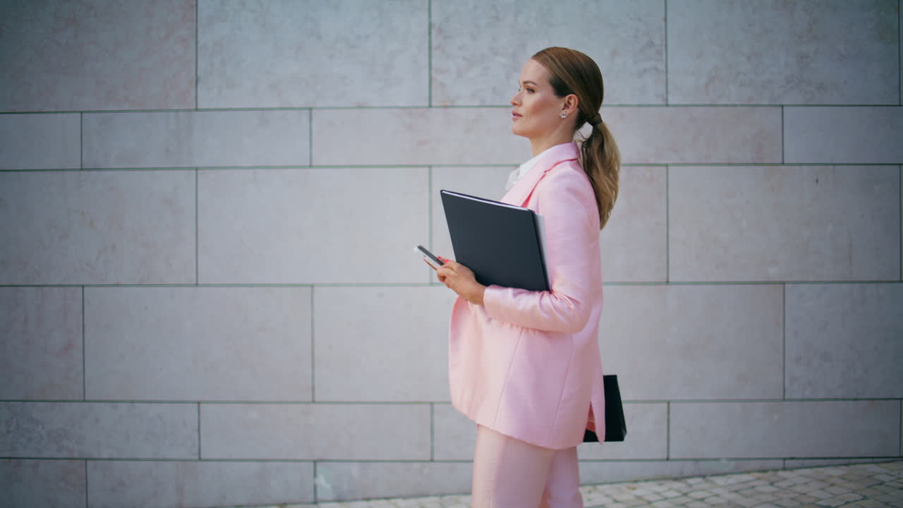 Busy woman manager walking street with documents folder. Lady looking smartphone