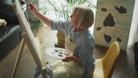 top view of senior female artist painting at home