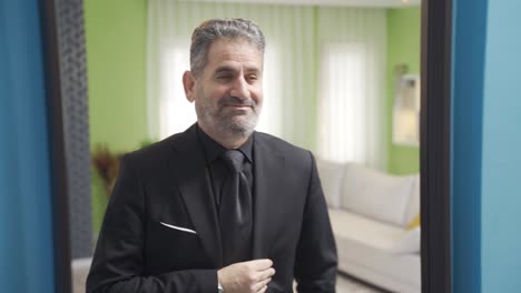 Happy-and-vivacious-mature-businessman-looking-at-himself-in-the-mirror-and-arranging-his-suit.