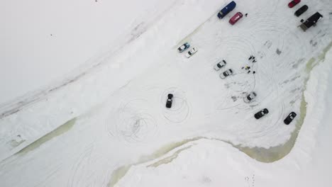 cheap sport cars drifting making donuts burnout on frozen lake in finland during cloudy day – aerial winter landscape with a frozen race track ltop down