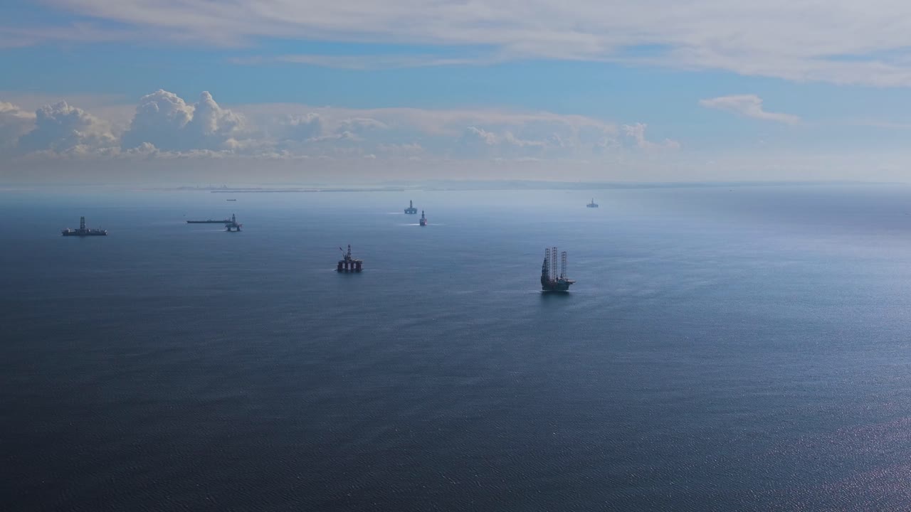 Drone shot of offshore oil rigs near Labuan, Malaysia, surrounded by calm blue ocean and distant clouds