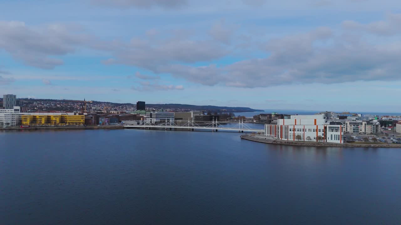 Veduta aerea del porto di Bergen in Norvegia con edifici sul lungomare, acqua calma e paesaggio urbano costiero con colline distanti sotto un cielo nuvoloso, suggestivo paesaggio nordico