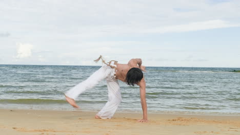 un tipo bailando capoeira en la playa.