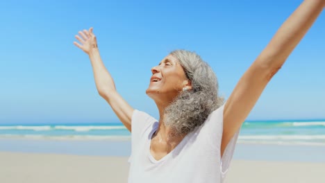 front view of active senior african american woman with arms stretched out standing on beach 4k