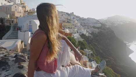 una joven viajera en santorini, grecia, se toma un momento para disfrutar de la puesta de sol.