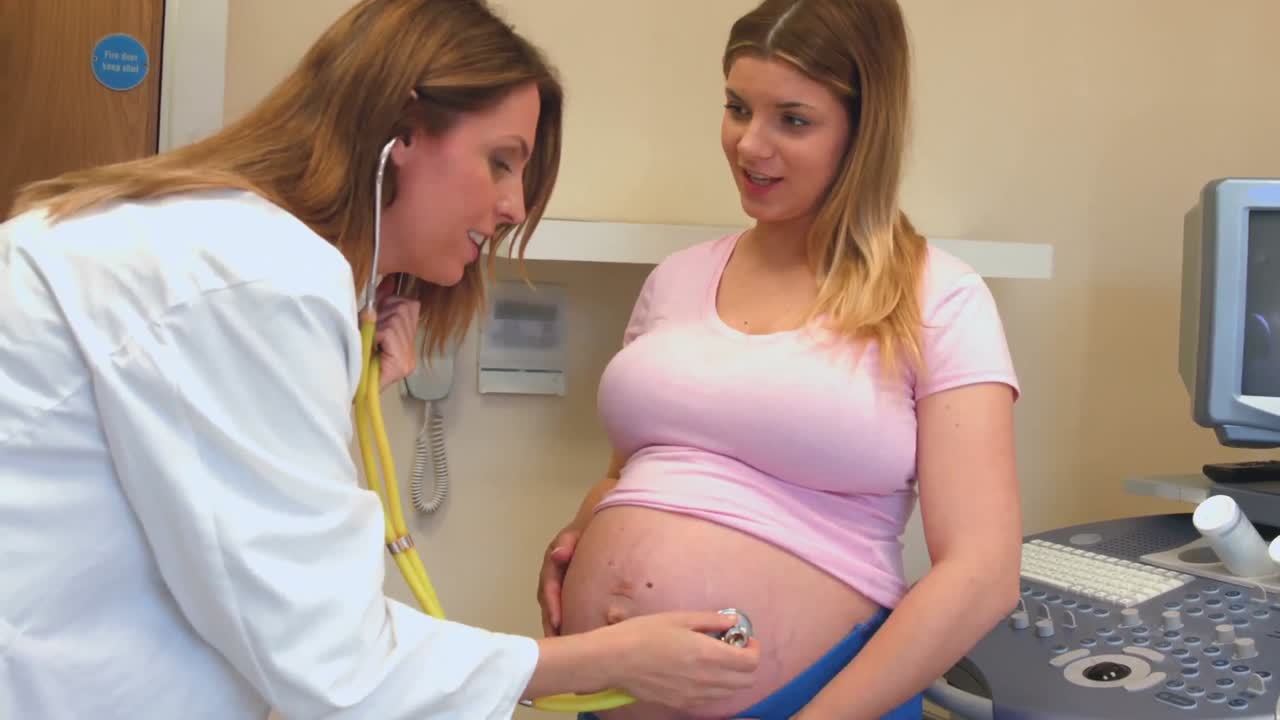 Médico usando um estetoscópio na barriga de uma gestante