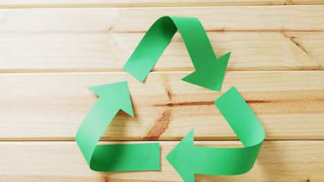 cierre de la basura y el símbolo de reciclaje de flechas de papel verde sobre fondo de madera