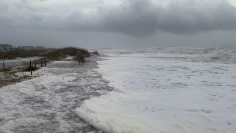 enormes olas de huracanes inundan la playa mientras la marejada ciclónica y los fuertes vientos golpean las dunas de arena