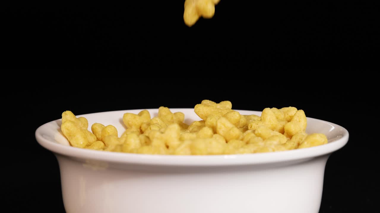 Star-shaped cereal pieces drop into a white bowl against a black background, creating a playful and dynamic visual