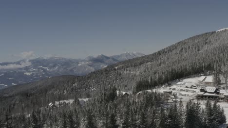 pohorje mountains in slovenia with with kope ski resort below covered in heavy snow, aerial pan left shot