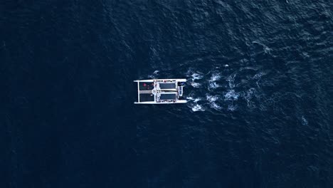 panorámica zenital de un catamarán navegando en aguas azules profundas, aislado en el océano