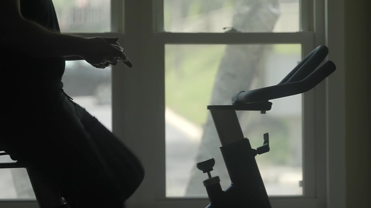 Silhouette person training on stationary bike playing video game indoors