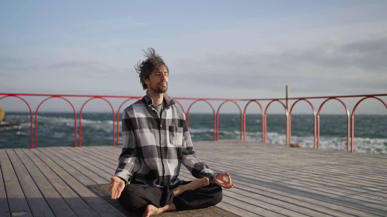 hombre meditando en un muelle de madera con vistas al mar