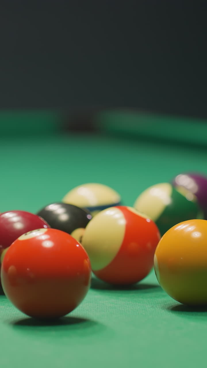 Blurred figure in light shirt and dark trousers leans over green pool table, gripping cue stick with deep concentration. Eyes locked on balls, posture steady, creating tension in dimly lit game room