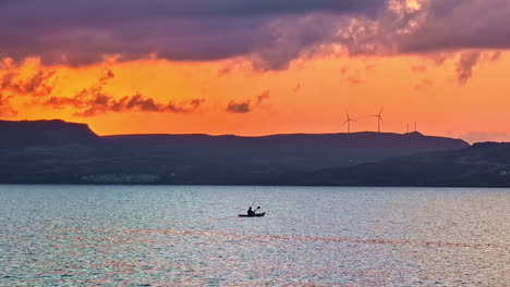 silhouette person paddling on the coastline of crete, dramatic evening in greece