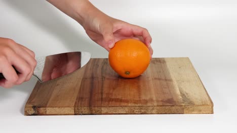 hands slicing an orange with a knife