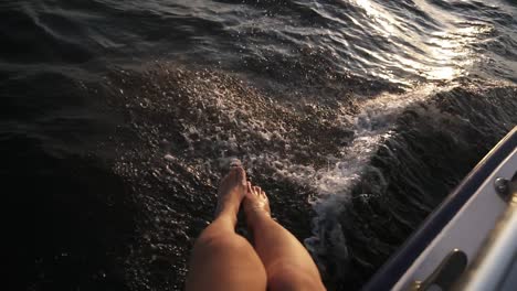 Top-View-Of-A-Nice-Women's-Legs-Playfully-Hanging-Above-Sea-From-Yacht-During-The-Marine-Walk