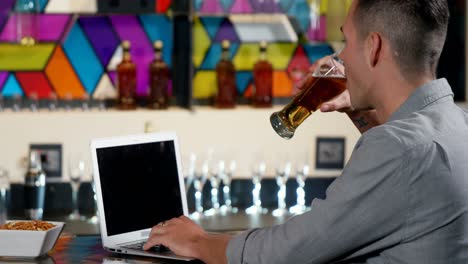 man using laptop while having a beer