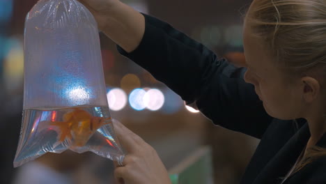 Woman-holds-in-hand-plastic-package-with-aquarium-gold-fish-in-the-shopping-mall-Hong-Kong-China