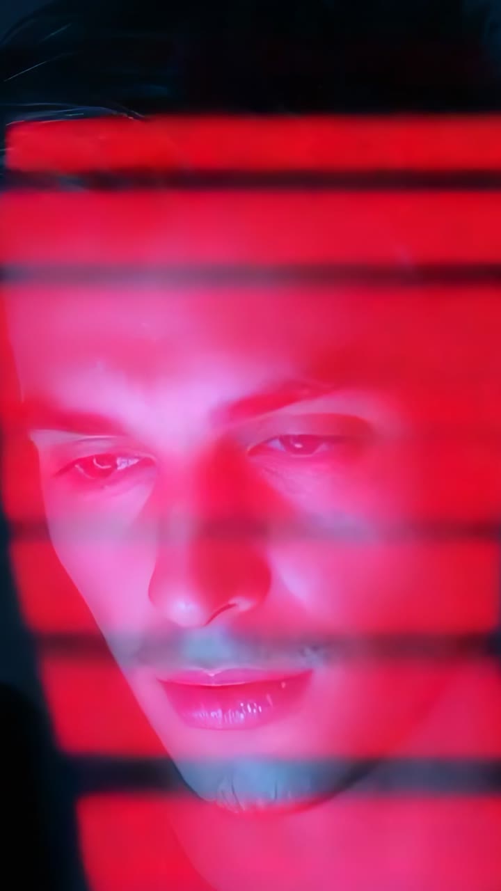 Video verticale: Un uomo che analizza i dati sullo schermo in una stanza buia reagisce ai cambiamenti delle bande rosse verticali