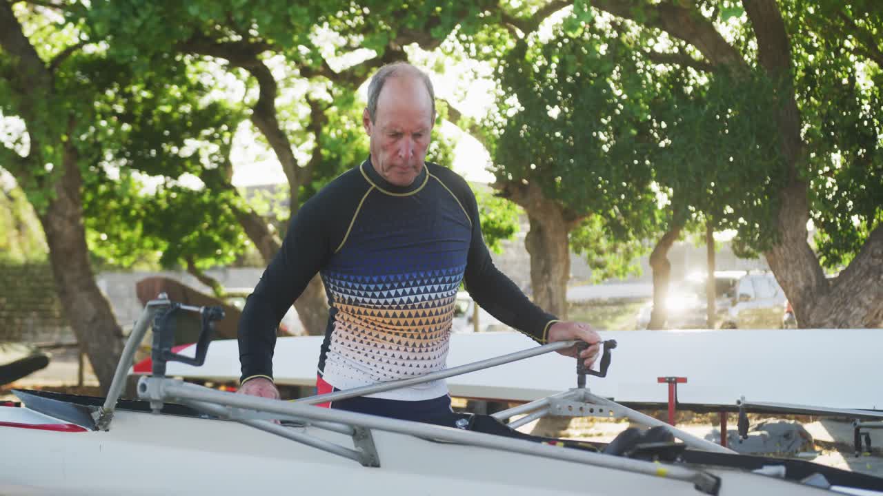 Senior caucasian man preparing rowing boat for the water
