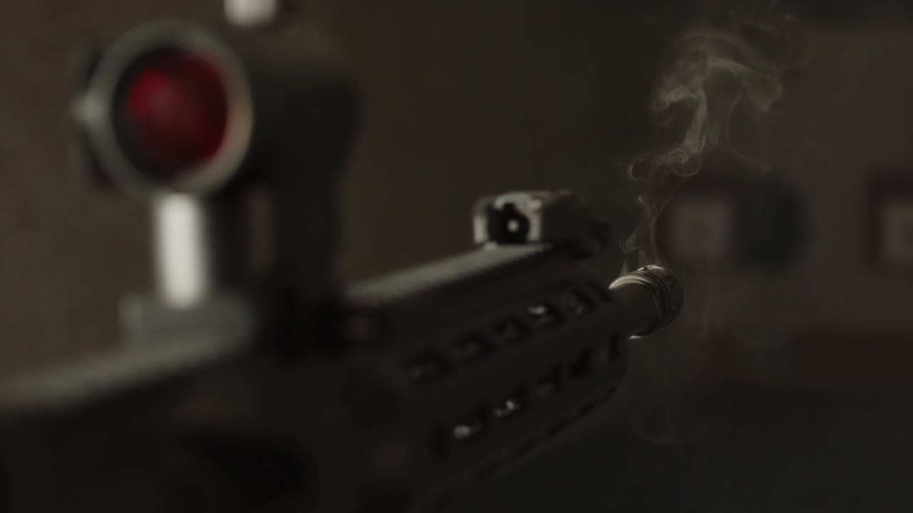 humo saliendo de un rifle de asalto ar-15 equipado con un punto rojo