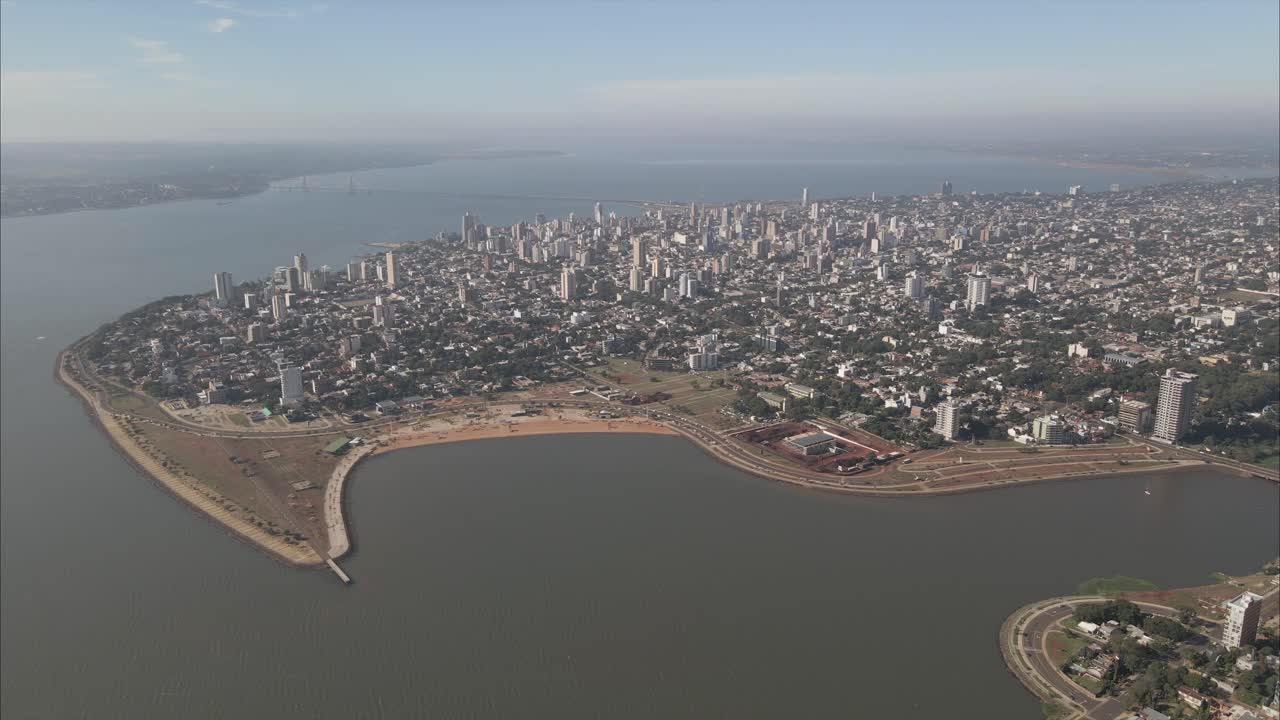 Vista aerea panoramica della città costiera di Posadas, Misiones, Argentina, ripresa con drone di una città costiera densamente popolata, cielo nuvoloso, con il Paraguay sullo sfondo.