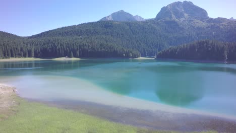 Agua-De-Lago-Limpia-Y-Verde-Con-Cimas-De-Montañas-Y-Bosques-Alrededor