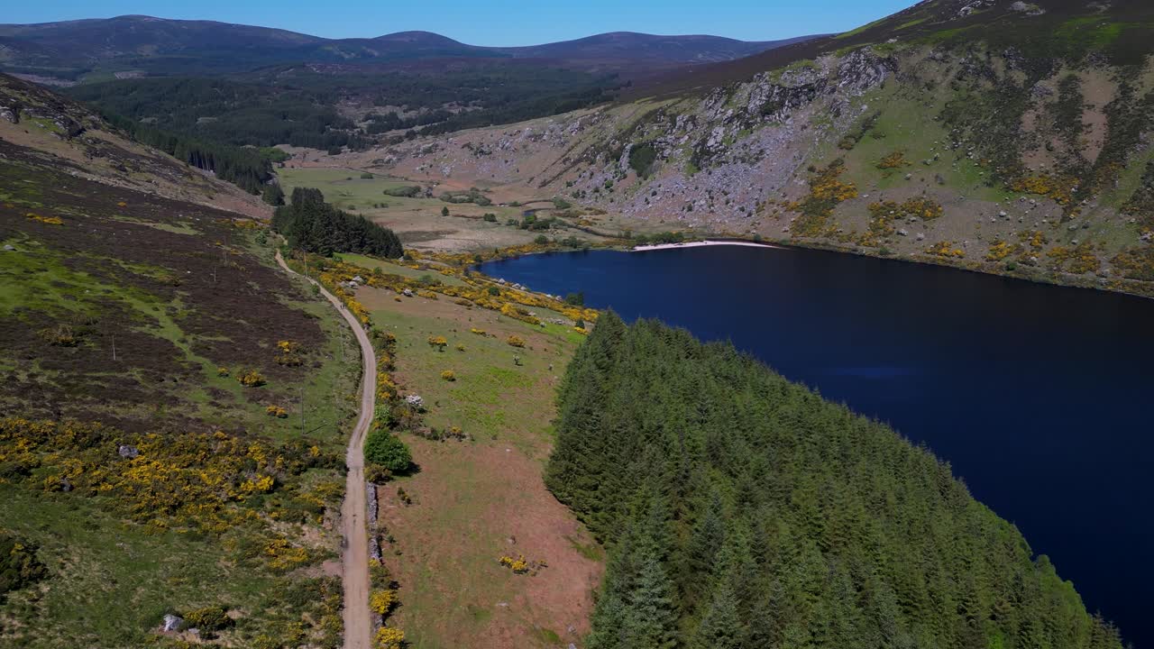 Smooth forward-moving aerial shot over rugged hillsides and deep blue waters at Lough Dan in County Wicklow, Ireland, capturing the serene landscape and sweeping natural beauty of the valley