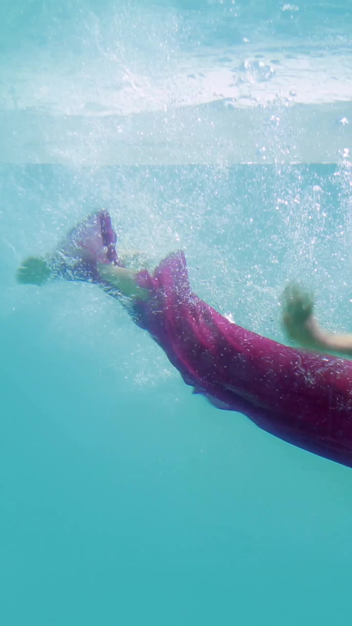 Brunetta in abito da sera che si tuffa in piscina
