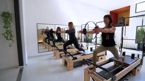 company of women doing lunges on pilates reformer