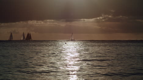sailboats on the ocean at sunset