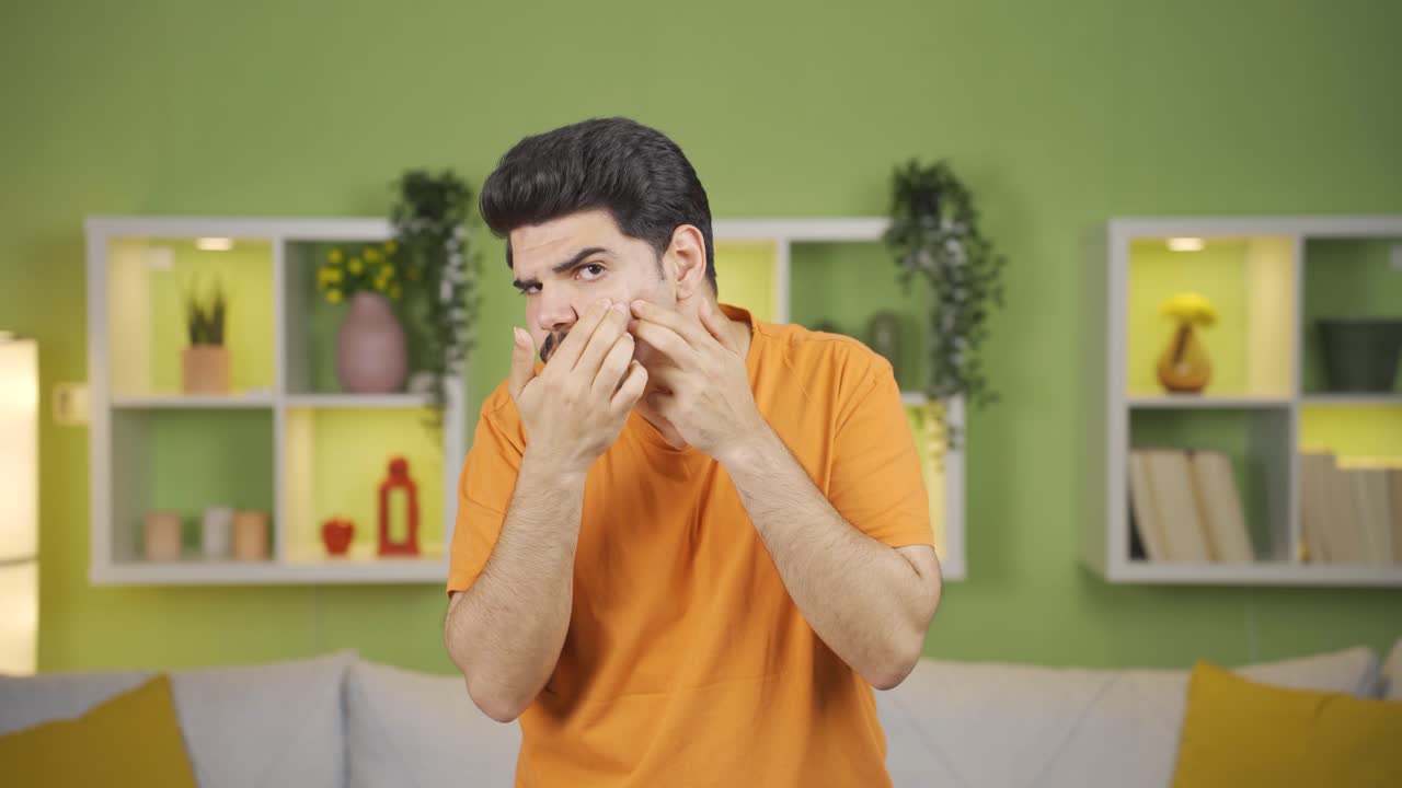 Giovane uomo con acne e cicatrici sul viso è infelice