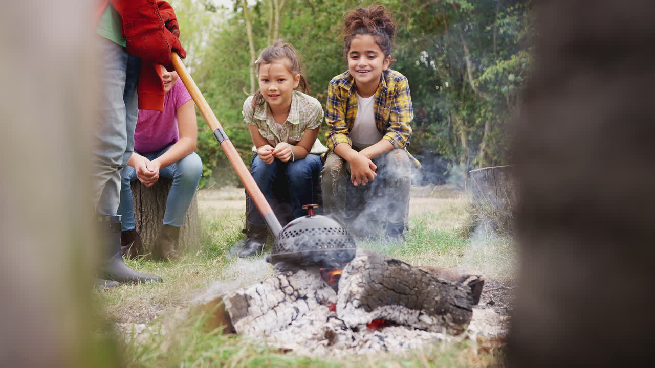 líder de equipo con un grupo de niños en un viaje de actividad al aire libre cocinando comida sobre un fuego de campamento