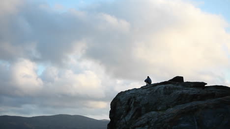 A-person-sits-at-the-top-of-a-rocky-mountain