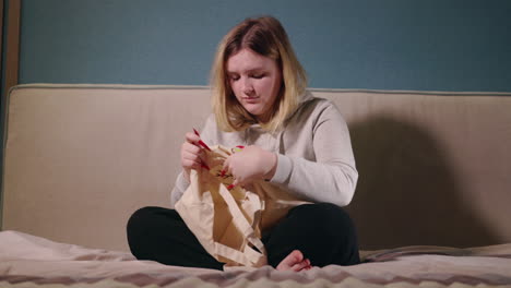 woman embroidering a tote bag on a bed