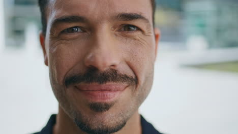 hombre de primer plano cara sonriente cámara en la ciudad soleada. retrato hombre de negocios