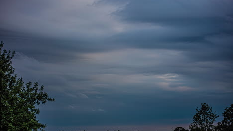 Low-angle-shot-of-dark-clouds-forming-and-covering-sky-on-a-windy-evening