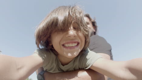 boy spinning in dads arms and filming himself on front camera